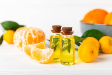 Tahta bir masada mandalina yağı. Bir şişe turunçgil yağı ve dilimlenmiş meyve. Mandalina kokulu mandalina yağı. Spa tedavileri için kozmetik yağı. Aromaterapi kavramı.
