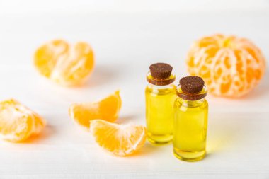 Tahta bir masada mandalina yağı. Bir şişe turunçgil yağı ve dilimlenmiş meyve. Mandalina kokulu mandalina yağı. Spa tedavileri için kozmetik yağı. Aromaterapi kavramı.