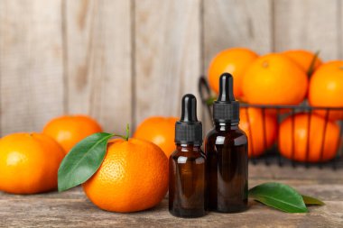 Tahta bir masada mandalina yağı. Bir şişe turunçgil yağı ve dilimlenmiş meyve. Mandalina kokulu mandalina yağı. Spa tedavileri için kozmetik yağı. Aromaterapi kavramı.