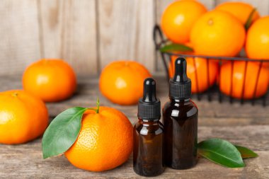 Tahta bir masada mandalina yağı. Bir şişe turunçgil yağı ve dilimlenmiş meyve. Mandalina kokulu mandalina yağı. Spa tedavileri için kozmetik yağı. Aromaterapi kavramı.