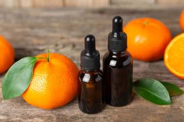 Tahta bir masada mandalina yağı. Bir şişe turunçgil yağı ve dilimlenmiş meyve. Mandalina kokulu mandalina yağı. Spa tedavileri için kozmetik yağı. Aromaterapi kavramı.