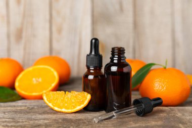 Tahta bir masada mandalina yağı. Bir şişe turunçgil yağı ve dilimlenmiş meyve. Mandalina kokulu mandalina yağı. Spa tedavileri için kozmetik yağı. Aromaterapi kavramı.