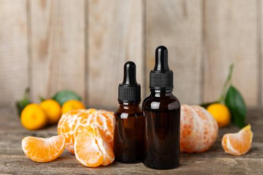 Tahta bir masada mandalina yağı. Bir şişe turunçgil yağı ve dilimlenmiş meyve. Mandalina kokulu mandalina yağı. Spa tedavileri için kozmetik yağı. Aromaterapi kavramı.
