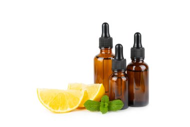 Limon dilimlenmiş limonlu bir şişede limon yağı ve beyaz arka planda izole edilmiş yapraklar. Limon yağı. Aromatik esanslı parfüm şişesi. Serum, limon özü. C vitamini. Doğal kozmetik ürünler. Aromaterapi. Spa mı? Metin için boşluk.