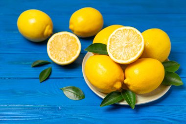 Tahta bir masada limon. Bir dilim taze limon. Turunçgil yapraklı taze limon. Limon suyu. Yemek ve içecek malzemeleri hazırlanıyor. Sağlıklı beslenme. Metin için C vitamini alanı.