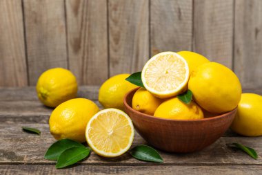 Tahta bir masada limon. Bir dilim taze limon. Turunçgil yapraklı taze limon. Limon suyu. Yemek ve içecek malzemeleri hazırlanıyor. Sağlıklı beslenme. Metin için C vitamini alanı.