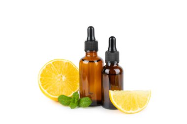 Limon dilimlenmiş limonlu bir şişede limon yağı ve beyaz arka planda izole edilmiş yapraklar. Limon yağı. Aromatik esanslı parfüm şişesi. Serum, limon özü. C vitamini. Doğal kozmetik ürünler. Aromaterapi. Spa mı? Metin için boşluk.