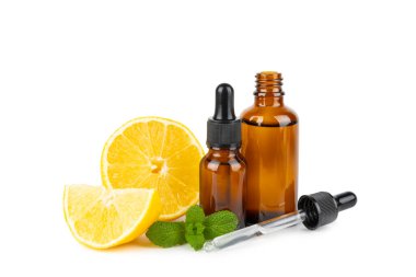 Limon dilimlenmiş limonlu bir şişede limon yağı ve beyaz arka planda izole edilmiş yapraklar. Limon yağı. Aromatik esanslı parfüm şişesi. Serum, limon özü. C vitamini. Doğal kozmetik ürünler. Aromaterapi. Spa mı? Metin için boşluk.