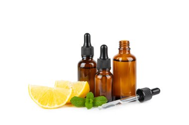 Limon dilimlenmiş limonlu bir şişede limon yağı ve beyaz arka planda izole edilmiş yapraklar. Limon yağı. Aromatik esanslı parfüm şişesi. Serum, limon özü. C vitamini. Doğal kozmetik ürünler. Aromaterapi. Spa mı? Metin için boşluk.