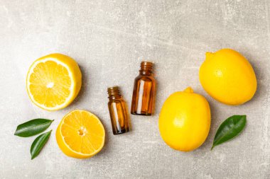 Limon dilimlenmiş limonlu bir şişede limon yağı ve ahşap bir arka planda yapraklar. Limon yağı. Aromatik esanslı parfüm şişesi. Serum, limon özü. C vitamini. Doğal kozmetik ürünler. Aromaterapi. Spa mı? Metin için boşluk.