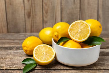 Tahta bir masada limon. Bir dilim taze limon. Turunçgil yapraklı taze limon. Limon suyu. Yemek ve içecek malzemeleri hazırlanıyor. Sağlıklı beslenme. Metin için C vitamini alanı.