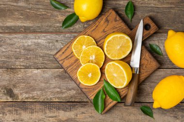 Tahta bir masada limon. Bir dilim taze limon. Turunçgil yapraklı taze limon. Limon suyu. Yemek ve içecek malzemeleri hazırlanıyor. Sağlıklı beslenme. Metin için C vitamini alanı.