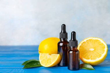 Limon dilimlenmiş limonlu bir şişede limon yağı ve ahşap bir arka planda yapraklar. Limon yağı. Aromatik esanslı parfüm şişesi. Serum, limon özü. C vitamini. Doğal kozmetik ürünler. Aromaterapi. Spa mı? Metin için boşluk.