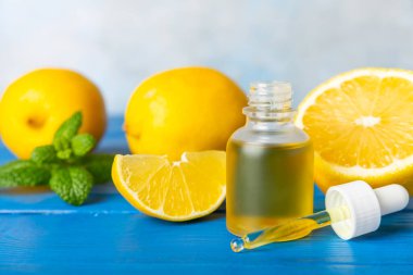 Limon dilimlenmiş limonlu bir şişede limon yağı ve ahşap bir arka planda yapraklar. Limon yağı. Aromatik esanslı parfüm şişesi. Serum, limon özü. C vitamini. Doğal kozmetik ürünler. Aromaterapi. Spa mı? Metin için boşluk.
