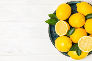 Tahta bir masada limon. Bir dilim taze limon. Turunçgil yapraklı taze limon. Limon suyu. Yemek ve içecek malzemeleri hazırlanıyor. Sağlıklı beslenme. Metin için C vitamini alanı.