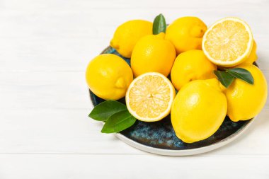 Tahta bir masada limon. Bir dilim taze limon. Turunçgil yapraklı taze limon. Limon suyu. Yemek ve içecek malzemeleri hazırlanıyor. Sağlıklı beslenme. Metin için C vitamini alanı.