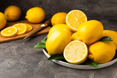 Tahta bir masada limon. Bir dilim taze limon. Turunçgil yapraklı taze limon. Limon suyu. Yemek ve içecek malzemeleri hazırlanıyor. Sağlıklı beslenme. Metin için C vitamini alanı.