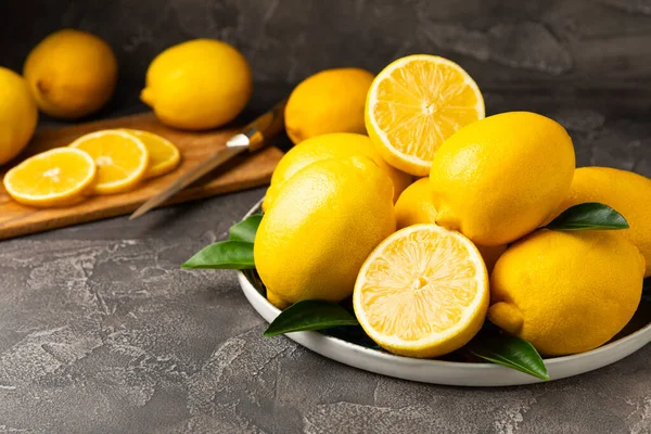 Tahta bir masada limon. Bir dilim taze limon. Turunçgil yapraklı taze limon. Limon suyu. Yemek ve içecek malzemeleri hazırlanıyor. Sağlıklı beslenme. Metin için C vitamini alanı.