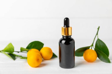 Tahta bir masada mandalina yağı. Bir şişe turunçgil yağı ve dilimlenmiş meyve. Mandalina kokulu mandalina yağı. Spa tedavileri için kozmetik yağı. Aromaterapi konsepti. Doğal kozmetikler. Geleneksel tıp. Metin için boşluk.