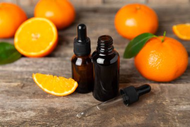 Tahta bir masada mandalina yağı. Bir şişe turunçgil yağı ve dilimlenmiş meyve. Mandalina kokulu mandalina yağı. Spa tedavileri için kozmetik yağı. Aromaterapi konsepti. Doğal kozmetikler. Geleneksel tıp. Metin için boşluk.