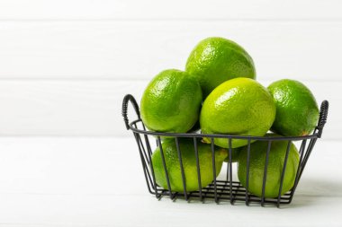 Tahta bir masada taze kireç. Masadaki bütün limon ve dilimler bir kasede. Citrus. C vitamini diyeti. Tropik meyveler. Yaz ferahlatıcı limonata ya da mojito konsepti. Mesaj için yer var. Boşluğu kopyala.