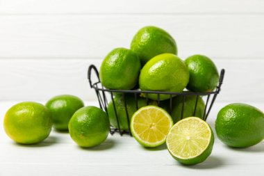Tahta bir masada taze kireç. Masadaki bütün limon ve dilimler bir kasede. Citrus. C vitamini diyeti. Tropik meyveler. Yaz ferahlatıcı limonata ya da mojito konsepti. Mesaj için yer var. Boşluğu kopyala.