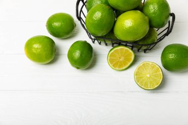 Tahta bir masada taze kireç. Masadaki bütün limon ve dilimler bir kasede. Citrus. C vitamini diyeti. Tropik meyveler. Yaz ferahlatıcı limonata ya da mojito konsepti. Mesaj için yer var. Boşluğu kopyala.
