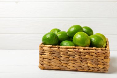 Tahta bir masada taze kireç. Masadaki bütün limon ve dilimler bir kasede. Citrus. C vitamini diyeti. Tropik meyveler. Yaz ferahlatıcı limonata ya da mojito konsepti. Mesaj için yer var. Boşluğu kopyala.