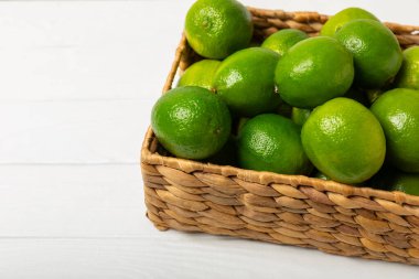 Tahta bir masada taze kireç. Masadaki bütün limon ve dilimler bir kasede. Citrus. C vitamini diyeti. Tropik meyveler. Yaz ferahlatıcı limonata ya da mojito konsepti. Mesaj için yer var. Boşluğu kopyala.
