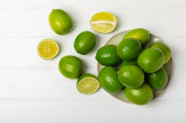 Tahta bir masada taze kireç. Masadaki bütün limon ve dilimler bir kasede. Citrus. C vitamini diyeti. Tropik meyveler. Yaz ferahlatıcı limonata ya da mojito konsepti. Mesaj için yer var. Boşluğu kopyala.