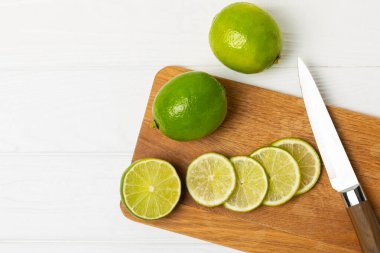Tahta bir masada taze kireç. Masadaki bütün limon ve dilimler bir kasede. Citrus. C vitamini diyeti. Tropik meyveler. Yaz ferahlatıcı limonata ya da mojito konsepti. Mesaj için yer var. Boşluğu kopyala.