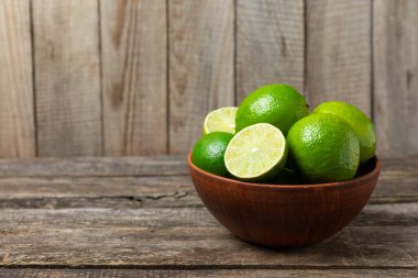 Tahta bir masada taze kireç. Masadaki bütün limon ve dilimler bir kasede. Citrus. C vitamini diyeti. Tropik meyveler. Yaz ferahlatıcı limonata ya da mojito konsepti. Mesaj için yer var. Boşluğu kopyala.