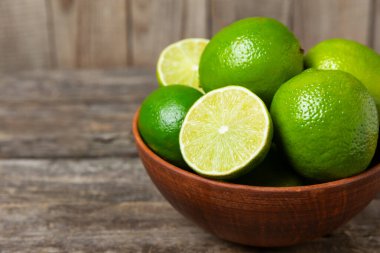 Tahta bir masada taze kireç. Masadaki bütün limon ve dilimler bir kasede. Citrus. C vitamini diyeti. Tropik meyveler. Yaz ferahlatıcı limonata ya da mojito konsepti. Mesaj için yer var. Boşluğu kopyala.