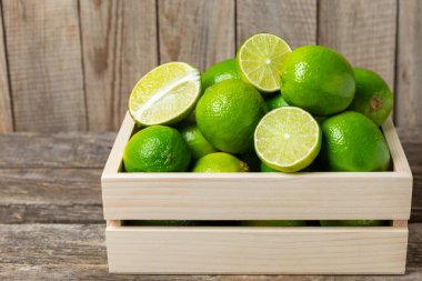 Tahta bir masada taze kireç. Masadaki bütün limon ve dilimler bir kasede. Citrus. C vitamini diyeti. Tropik meyveler. Yaz ferahlatıcı limonata ya da mojito konsepti. Mesaj için yer var. Boşluğu kopyala.