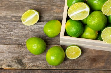 Tahta bir masada taze kireç. Masadaki bütün limon ve dilimler bir kasede. Citrus. C vitamini diyeti. Tropik meyveler. Yaz ferahlatıcı limonata ya da mojito konsepti. Mesaj için yer var. Boşluğu kopyala.