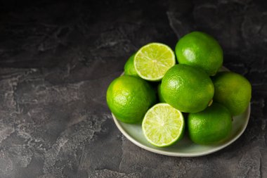 Tahta bir masada taze kireç. Masadaki bütün limon ve dilimler bir kasede. Citrus. C vitamini diyeti. Tropik meyveler. Yaz ferahlatıcı limonata ya da mojito konsepti. Mesaj için yer var. Boşluğu kopyala.