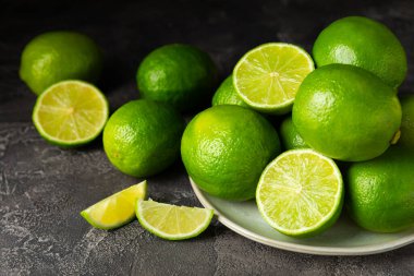 Tahta bir masada taze kireç. Masadaki bütün limon ve dilimler bir kasede. Citrus. C vitamini diyeti. Tropik meyveler. Yaz ferahlatıcı limonata ya da mojito konsepti. Mesaj için yer var. Boşluğu kopyala.