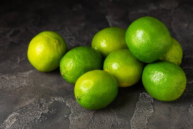 Tahta bir masada taze kireç. Masadaki bütün limon ve dilimler bir kasede. Citrus. C vitamini diyeti. Tropik meyveler. Yaz ferahlatıcı limonata ya da mojito konsepti. Mesaj için yer var. Boşluğu kopyala.