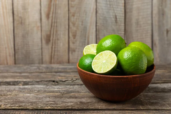 Tahta bir masada taze kireç. Masadaki bütün limon ve dilimler bir kasede. Citrus. C vitamini diyeti. Tropik meyveler. Yaz ferahlatıcı limonata ya da mojito konsepti. Mesaj için yer var. Boşluğu kopyala.