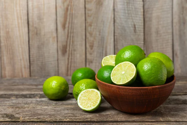 Tahta bir masada taze kireç. Masadaki bütün limon ve dilimler bir kasede. Citrus. C vitamini diyeti. Tropik meyveler. Yaz ferahlatıcı limonata ya da mojito konsepti. Mesaj için yer var. Boşluğu kopyala.