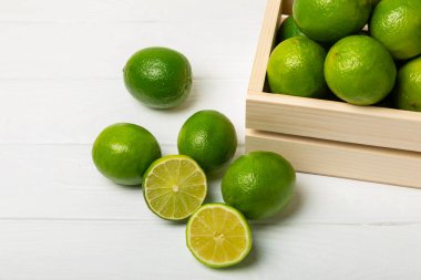 Tahta bir masada taze kireç. Masadaki bütün limon ve dilimler bir kasede. Citrus. C vitamini diyeti. Tropik meyveler. Yaz ferahlatıcı limonata ya da mojito konsepti. Mesaj için yer var. Boşluğu kopyala.