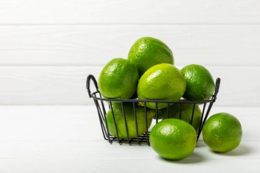 Tahta bir masada taze kireç. Masadaki bütün limon ve dilimler bir kasede. Citrus. C vitamini diyeti. Tropik meyveler. Yaz ferahlatıcı limonata ya da mojito konsepti. Mesaj için yer var. Boşluğu kopyala.