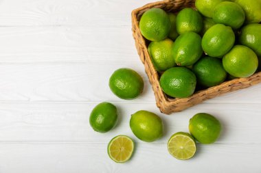 Tahta bir masada taze kireç. Masadaki bütün limon ve dilimler bir kasede. Citrus. C vitamini diyeti. Tropik meyveler. Yaz ferahlatıcı limonata ya da mojito konsepti. Mesaj için yer var. Boşluğu kopyala.