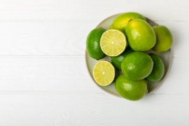Tahta bir masada taze kireç. Masadaki bütün limon ve dilimler bir kasede. Citrus. C vitamini diyeti. Tropik meyveler. Yaz ferahlatıcı limonata ya da mojito konsepti. Mesaj için yer var. Boşluğu kopyala.