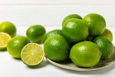 Tahta bir masada taze kireç. Masadaki bütün limon ve dilimler bir kasede. Citrus. C vitamini diyeti. Tropik meyveler. Yaz ferahlatıcı limonata ya da mojito konsepti. Mesaj için yer var. Boşluğu kopyala.