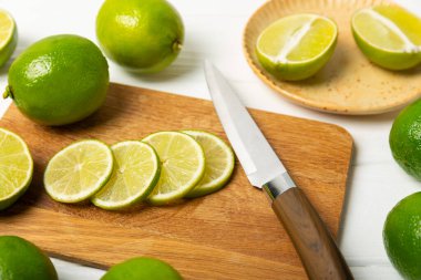 Tahta bir masada taze kireç. Masadaki bütün limon ve dilimler bir kasede. Citrus. C vitamini diyeti. Tropik meyveler. Yaz ferahlatıcı limonata ya da mojito konsepti. Mesaj için yer var. Boşluğu kopyala.