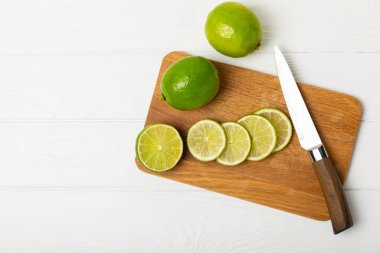 Tahta bir masada taze kireç. Masadaki bütün limon ve dilimler bir kasede. Citrus. C vitamini diyeti. Tropik meyveler. Yaz ferahlatıcı limonata ya da mojito konsepti. Mesaj için yer var. Boşluğu kopyala.