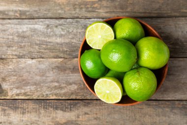 Tahta bir masada taze kireç. Masadaki bütün limon ve dilimler bir kasede. Citrus. C vitamini diyeti. Tropik meyveler. Yaz ferahlatıcı limonata ya da mojito konsepti. Mesaj için yer var. Boşluğu kopyala.