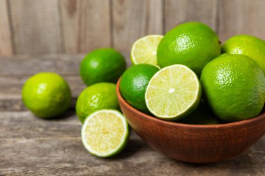 Tahta bir masada taze kireç. Masadaki bütün limon ve dilimler bir kasede. Citrus. C vitamini diyeti. Tropik meyveler. Yaz ferahlatıcı limonata ya da mojito konsepti. Mesaj için yer var. Boşluğu kopyala.