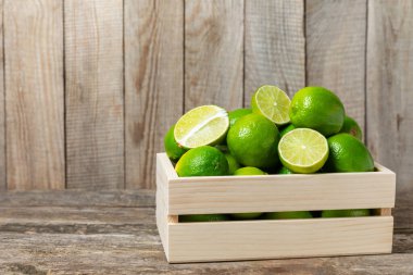 Tahta bir masada taze kireç. Masadaki bütün limon ve dilimler bir kasede. Citrus. C vitamini diyeti. Tropik meyveler. Yaz ferahlatıcı limonata ya da mojito konsepti. Mesaj için yer var. Boşluğu kopyala.